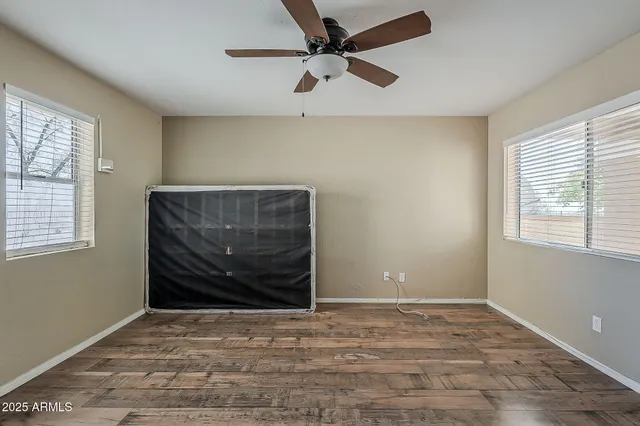 a view of empty room with wooden floor and fan