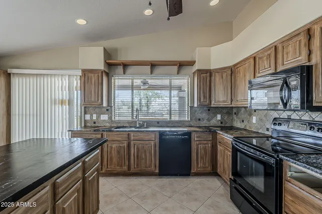 a kitchen with stainless steel appliances granite countertop stove top oven a sink dishwasher and cabinets with wooden floor