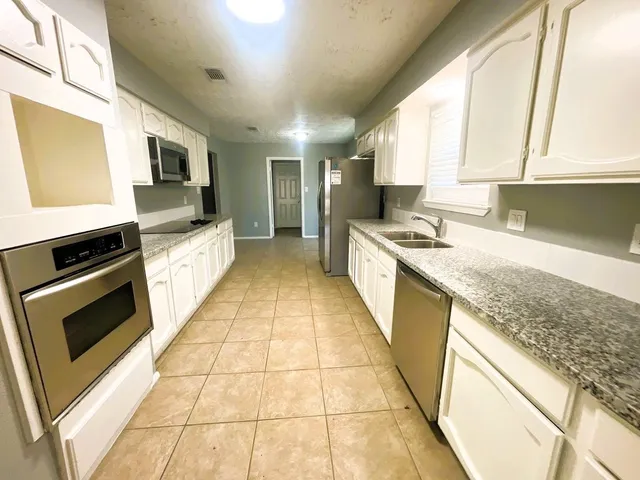 a kitchen with stainless steel appliances granite countertop a stove a sink and a microwave