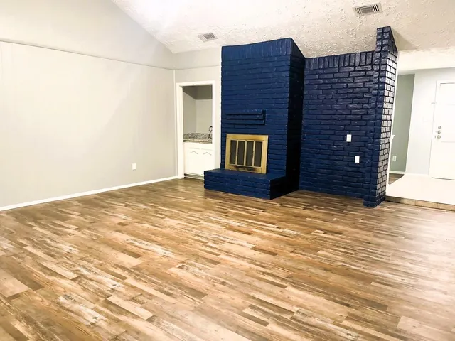 a view of an empty room with wooden floor and cabinet