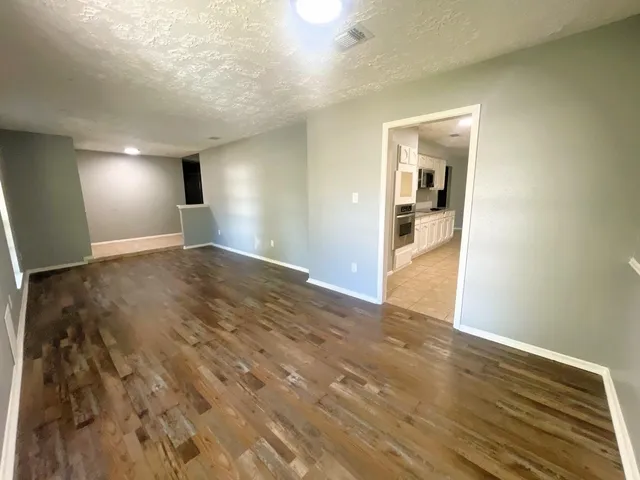 a view of a big room with wooden floor and windows