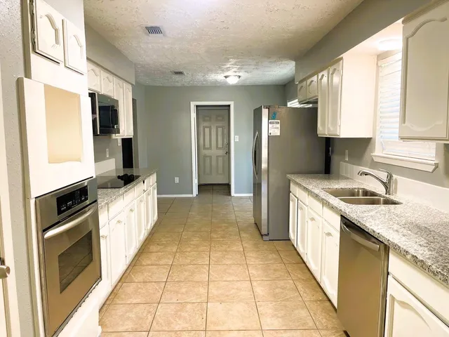 a kitchen with granite countertop a stove a sink and a refrigerator