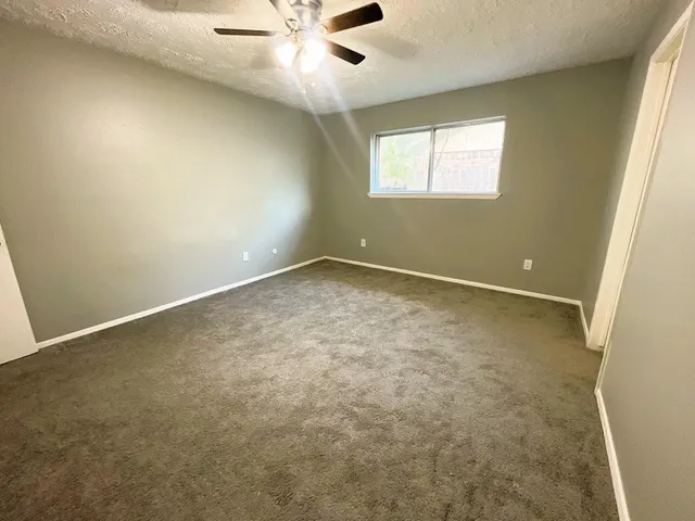 an empty room with a window and a fan