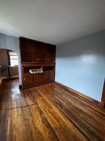 a view of kitchen and empty room with wooden floor