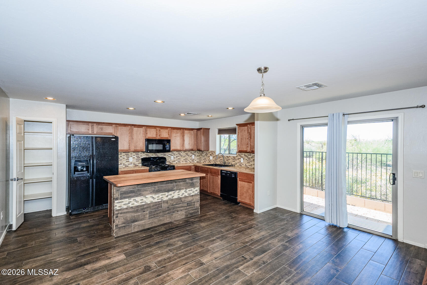 728 South Porter Routh Place Vail, AZ 85641 - Photo 7 of 36 a large kitchen with kitchen island a stove a refrigerator a sink dishwasher with a dining table and chairs with wooden floor