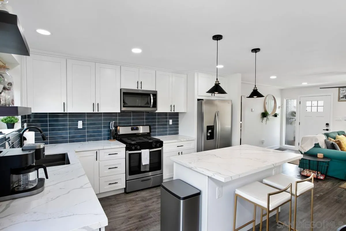 3109 Hawk Street San Diego, CA 92103 - Photo 18 of 75 a kitchen with stainless steel appliances kitchen island granite countertop a stove a sink a microwave a refrigerator and white cabinets with wooden floor