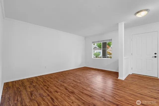 a view of an empty room with wooden floor and a window