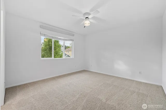 an empty room with a fan & a window