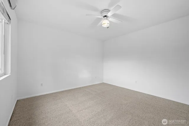 an empty room with a ceiling fan and carpet