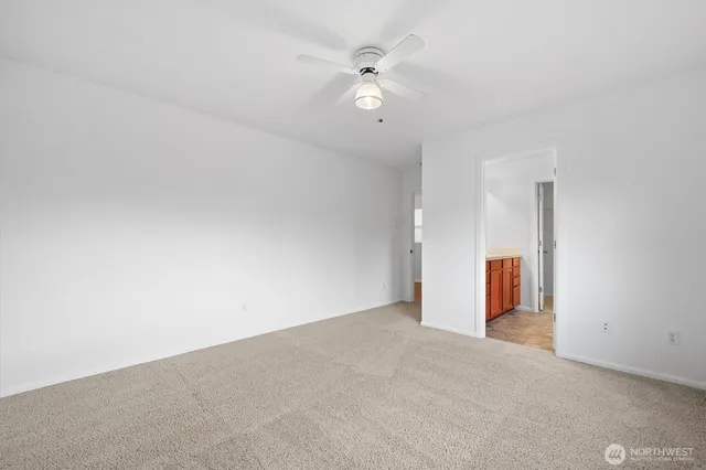 an empty room with windows and ceiling fan