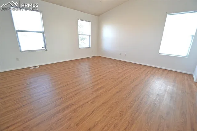 an empty room with wooden floor and windows