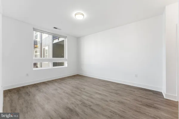 an empty room with wooden floor and windows