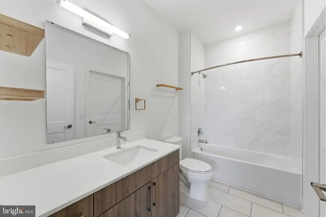 a bathroom with a granite countertop sink a toilet and shower