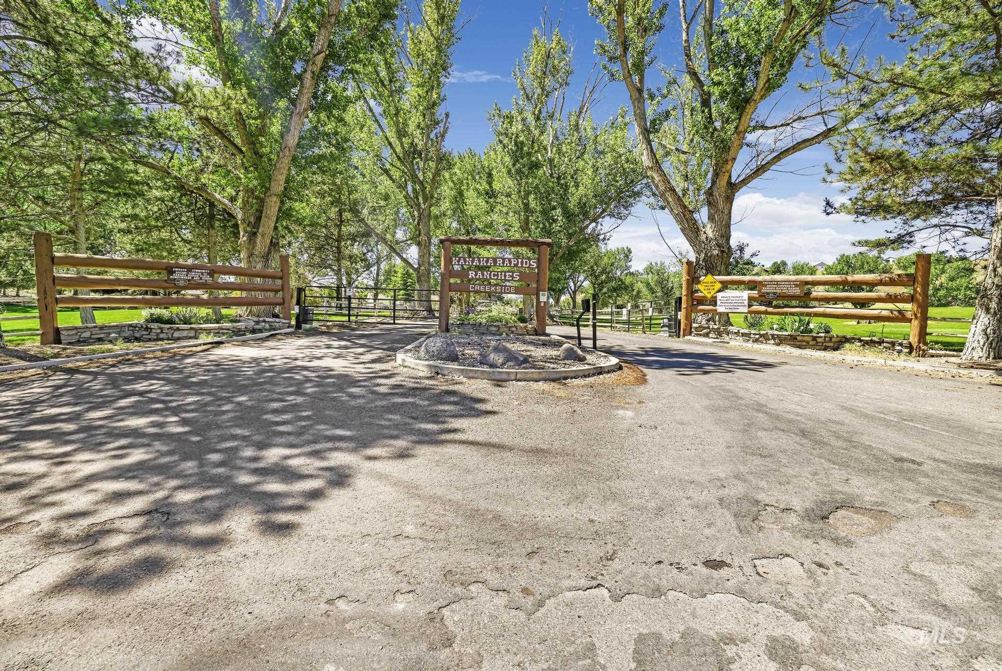 4485 Silver Creek Road Buhl, ID 83316 - Photo 45 of 49 Gated entrance featuring a wood and stone sign, post-and-rail fencing, and mature trees providing natural shading