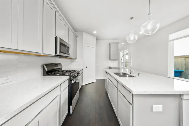 a large white kitchen with lots of counter space a sink appliances and cabinets
