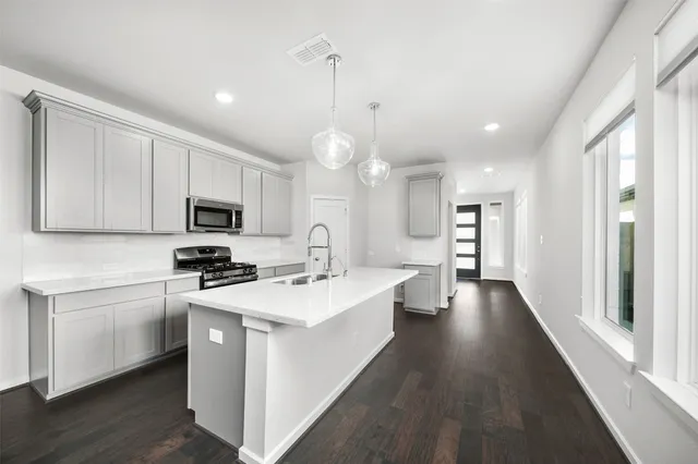 a large kitchen with stainless steel appliances granite countertop a stove a sink and a microwave