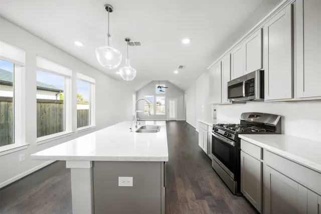 a large white kitchen with white cabinets and wooden floor