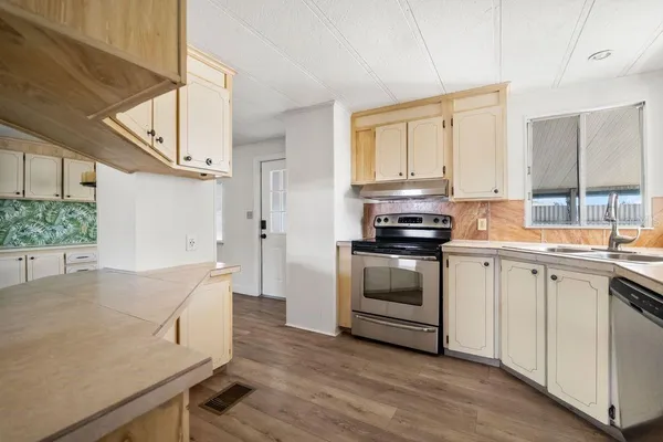 a kitchen with stainless steel appliances white cabinets and wooden floor