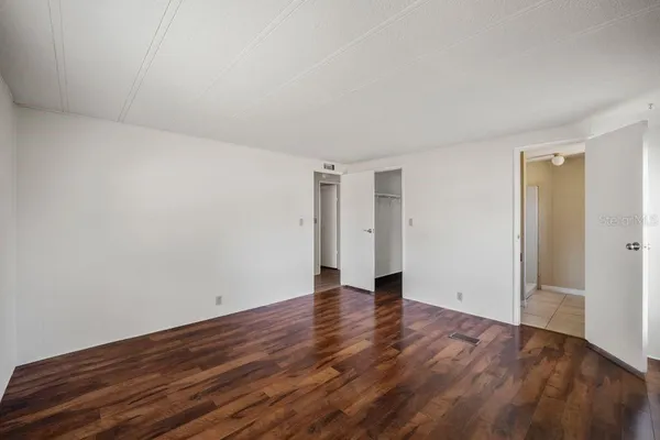 a view of an empty room with wooden floor and closet