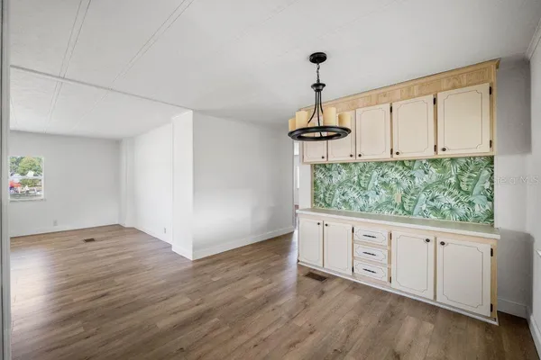 a view of a big room with wooden floor and a kitchen