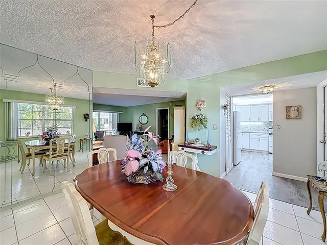 a view of a dining room with furniture a chandelier and kitchen view