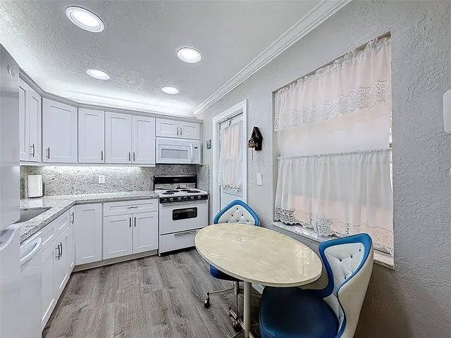 a kitchen with stainless steel appliances granite countertop a stove a sink dishwasher and a refrigerator with wooden floor