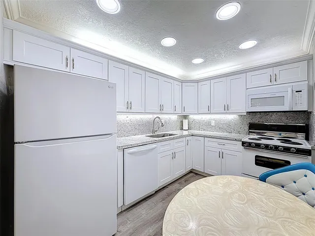 a kitchen with sink a refrigerator and white cabinets