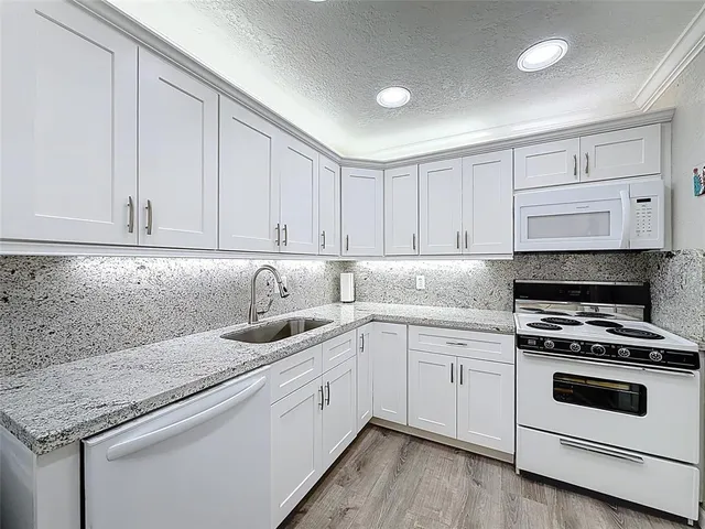 a kitchen with granite countertop white cabinets and white appliances