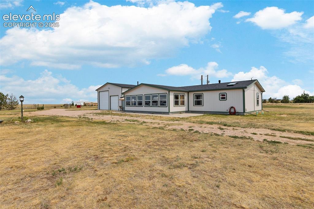 1350 South Calhan Highway Yoder, CO 80864 - Photo 2 of 45 Expansive property featuring a single-story residence with a multi-pane window sunroom and an attached two-door garage