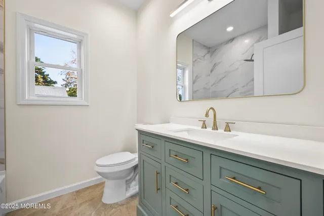 a bathroom with a granite countertop toilet sink and mirror