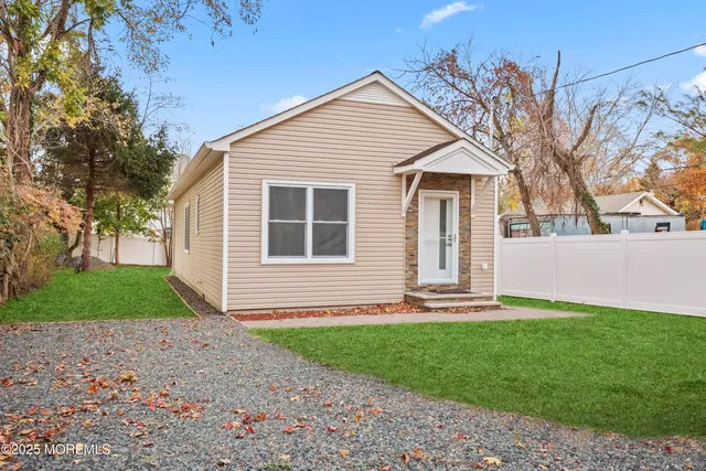 a front view of a house with a yard and large tree