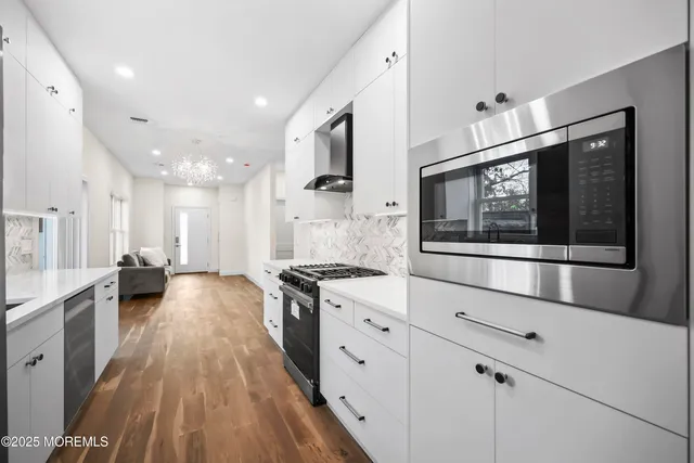 a large kitchen with stainless steel appliances a stove a sink and a microwave