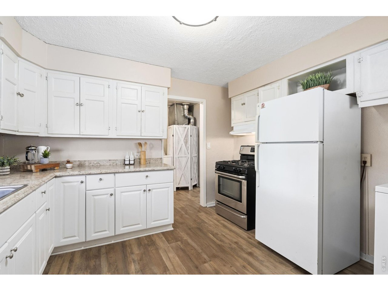 1416 6th Street Greeley, CO 80631 - Photo 11 of 50 a kitchen with granite countertop a refrigerator sink stove and white cabinets