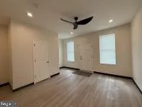 an empty room with wooden floor a ceiling fan and windows