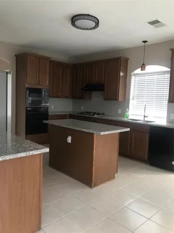 a kitchen with stainless steel appliances granite countertop a sink a stove a refrigerator a center island and a window