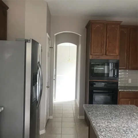 a kitchen with granite countertop a refrigerator and microwave