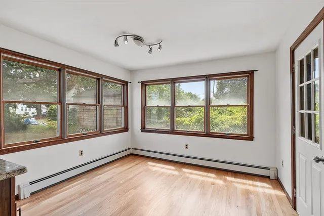 a view of an empty room with a window and a kitchen view