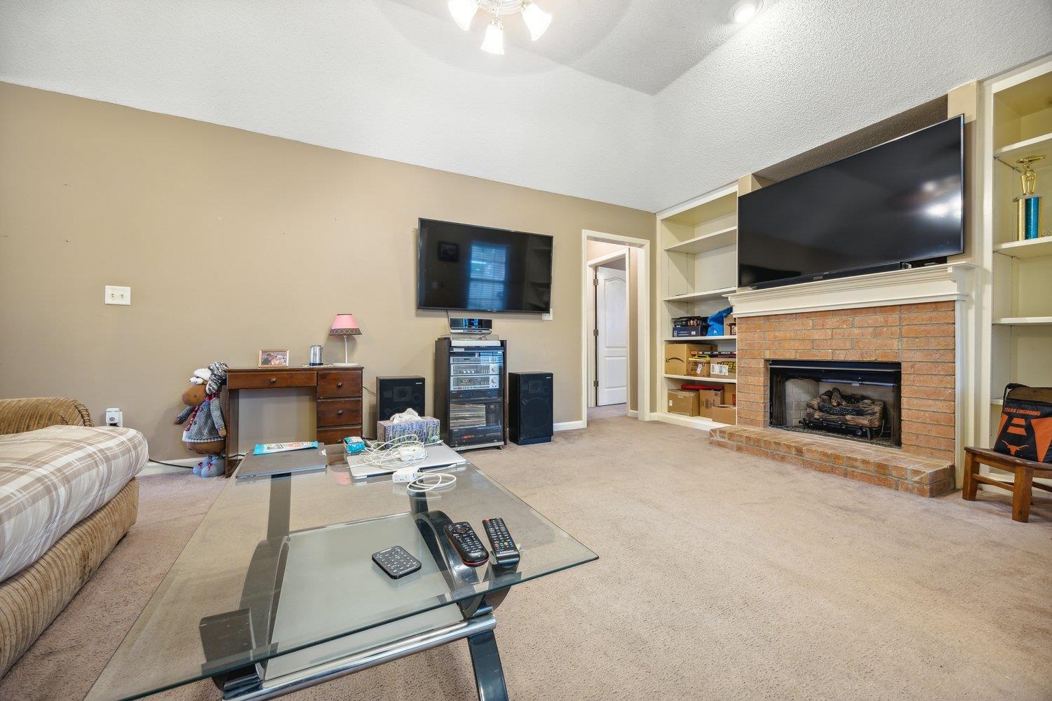 10076 Cross Ridge Road Cordova, TN 38018 - Photo 8 of 21 Living room featuring a textured ceiling, built in shelves, light colored carpet, a brick fireplace, and ceiling fan