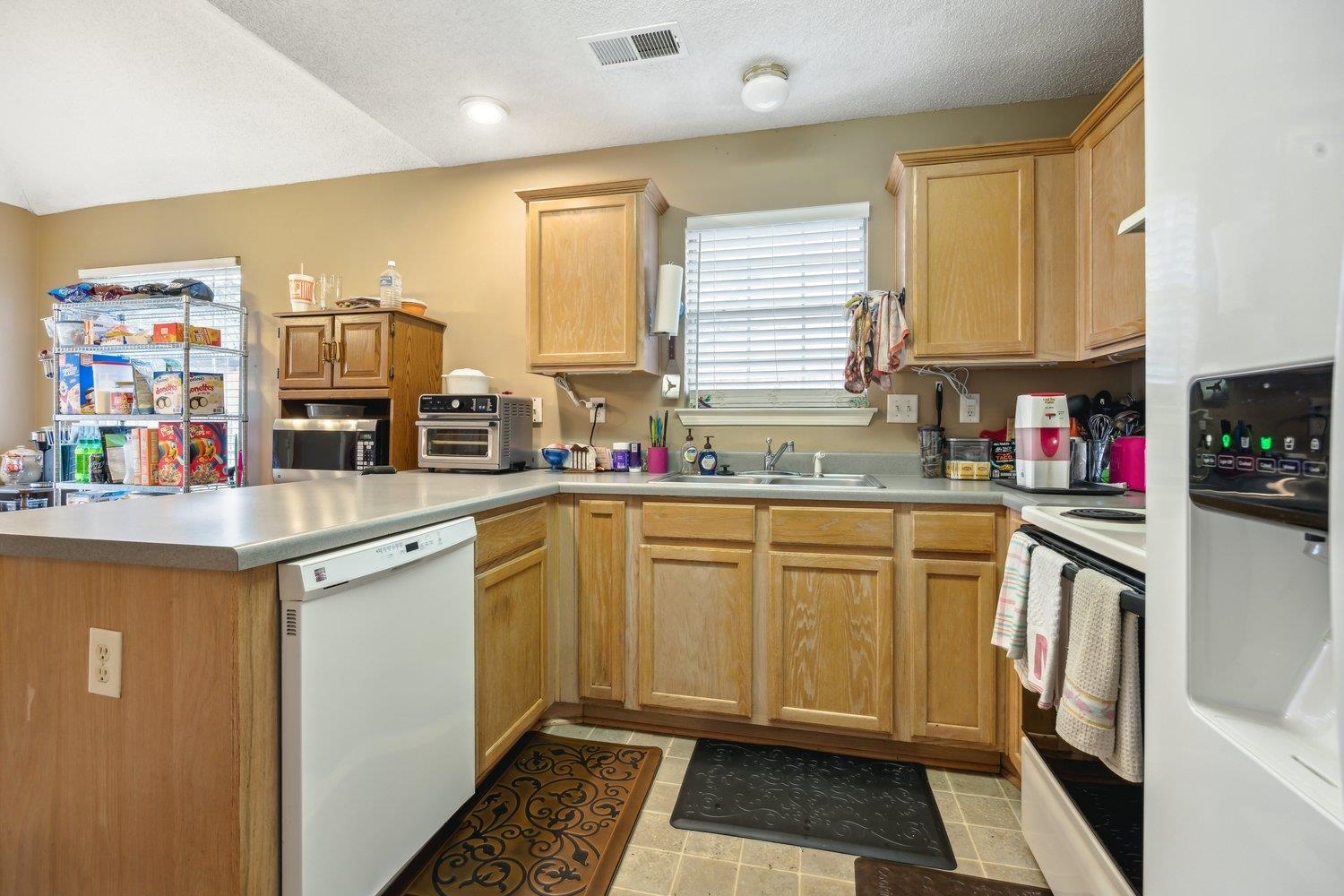 10076 Cross Ridge Road Cordova, TN 38018 - Photo 9 of 21 Kitchen featuring a textured ceiling, kitchen peninsula, sink, and white appliances