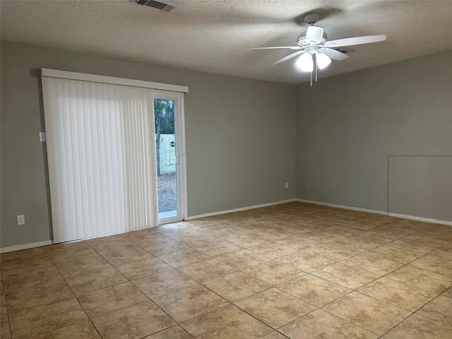 a view of an empty room and chandelier fan