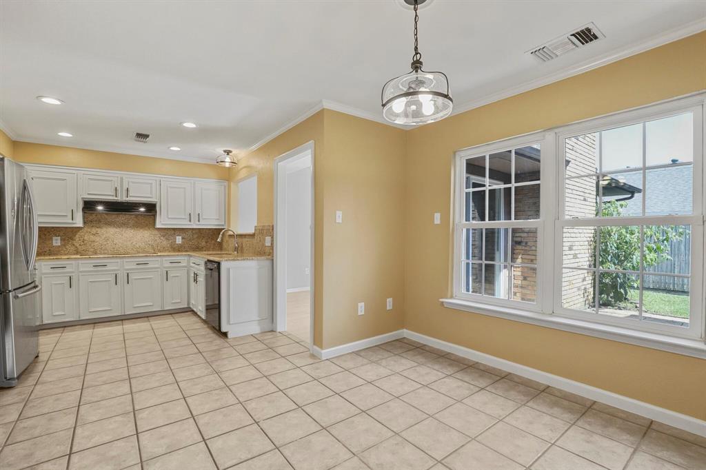 15632 Moondust Drive Dallas, TX 75248 - Photo 15 of 36 Kitchen featuring white cabinetry, pendant lighting, freestanding refrigerator, crown molding, and light tile patterned floors