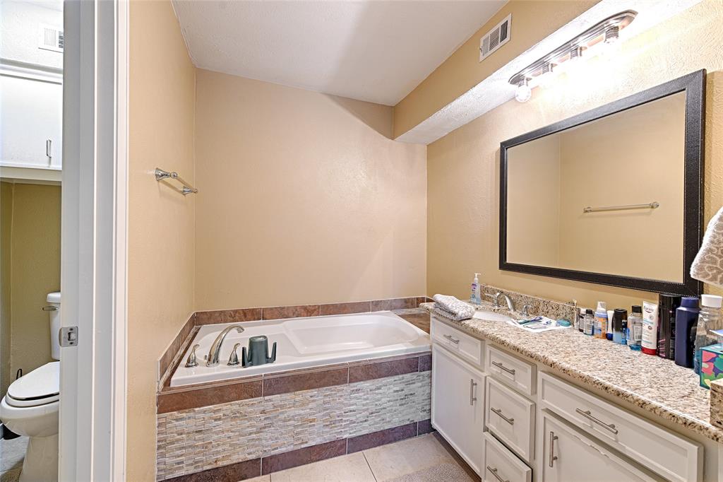 15632 Moondust Drive Dallas, TX 75248 - Photo 25 of 36 a bathroom with a granite countertop sink and a mirror