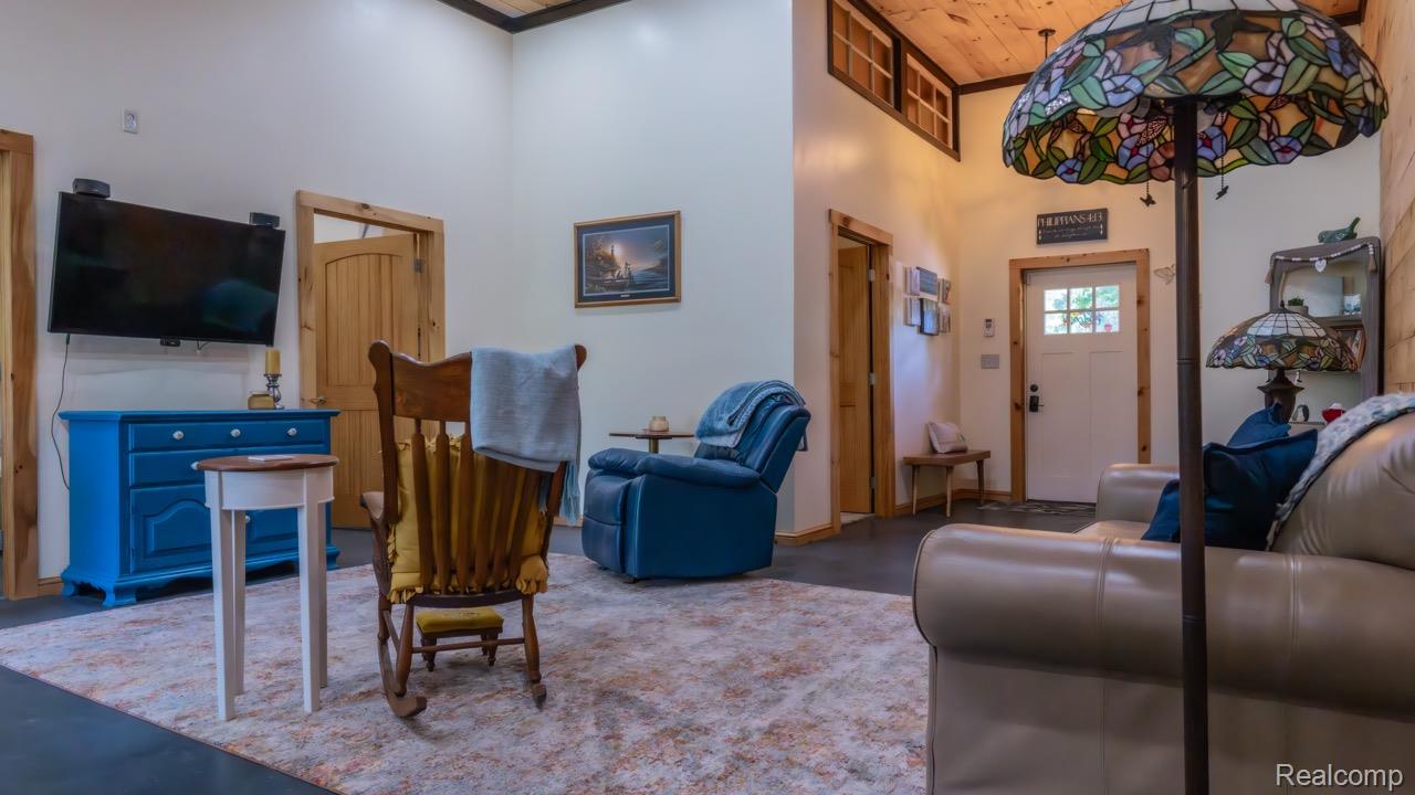 2418 South 41st Road South Cadillac, MI 49601 - Photo 8 of 57 Open-concept living area featuring vaulted ceilings, light-tone walls, wood-finish flooring, and natural wood trim accents