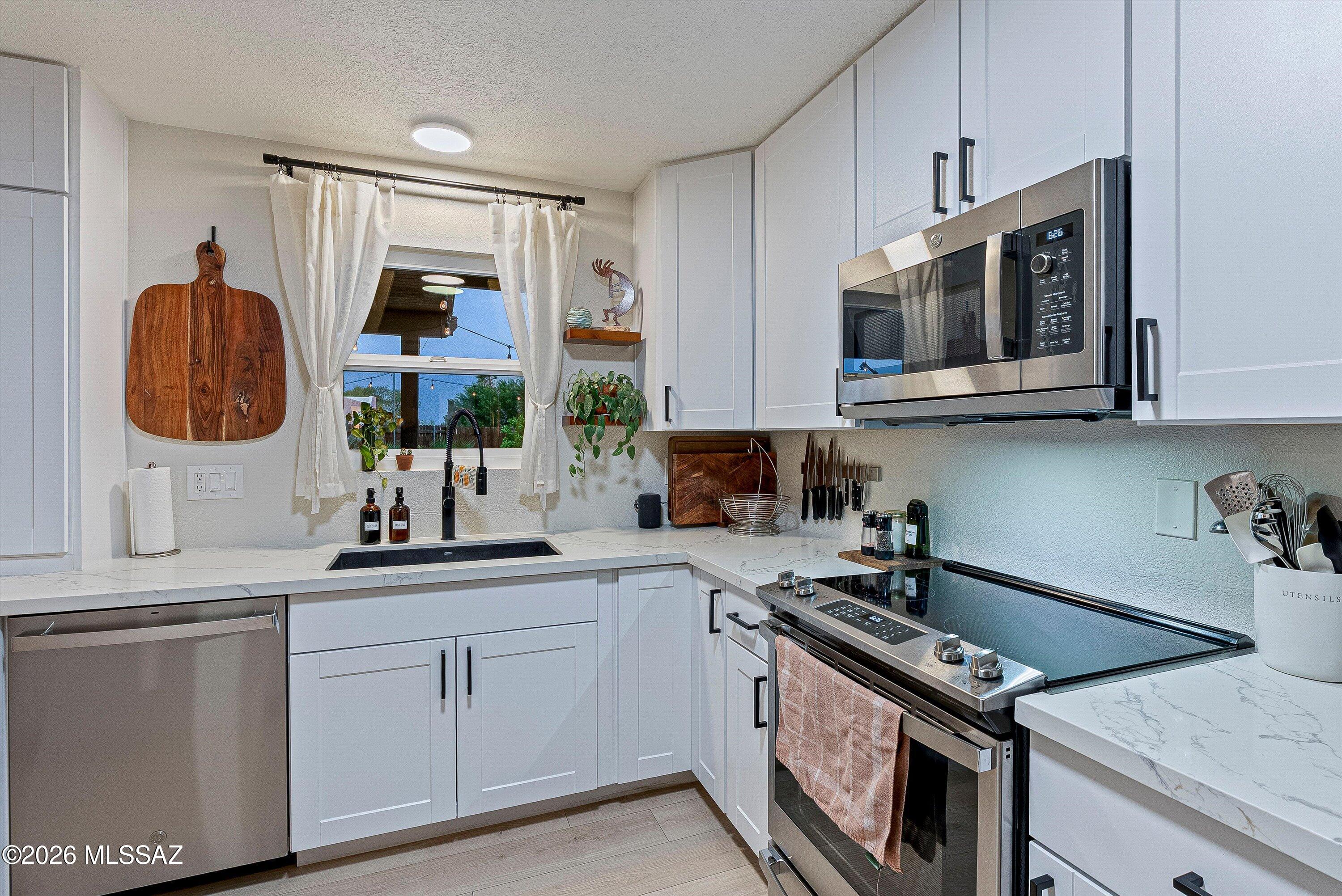 3949 West Mars Street Tucson, AZ 85741 - Photo 21 of 27 a kitchen with stainless steel appliances granite countertop a stove a sink and a microwave