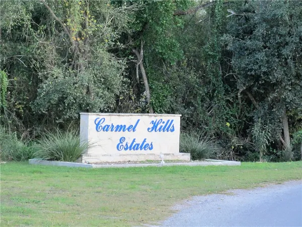 a sign that is sitting in the grass next to a road