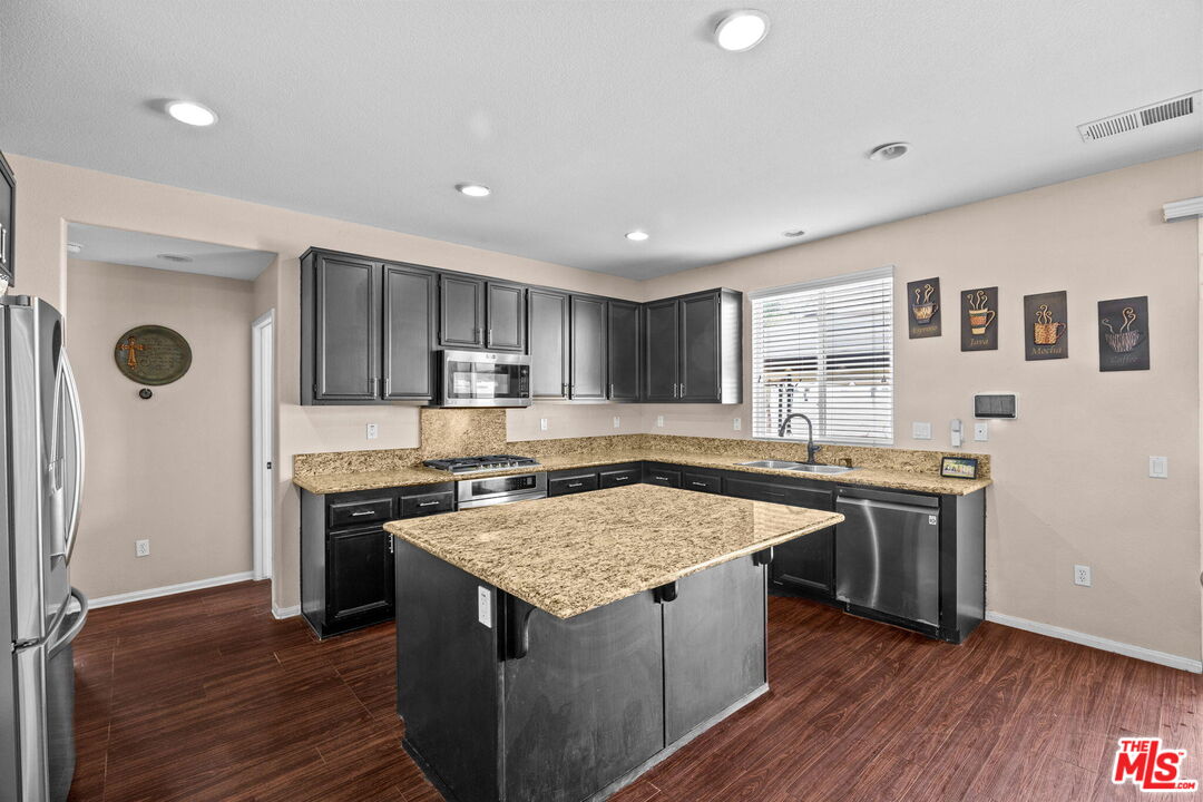 26692 Rim Creek Path Menifee, CA 92584 - Photo 9 of 41 a kitchen with stainless steel appliances granite countertop a stove a sink dishwasher and a refrigerator