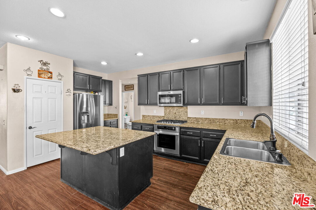 26692 Rim Creek Path Menifee, CA 92584 - Photo 10 of 41 a kitchen with stainless steel appliances granite countertop a stove a sink dishwasher and a refrigerator with wooden floor