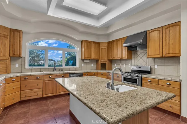 a kitchen with granite countertop a sink window and cabinets