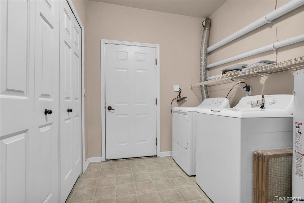 1150 Rial Lake Drive Howell, MI 48843 - Photo 19 of 24 Utility area featuring a washer and dryer, wire shelving, and paneled doors
