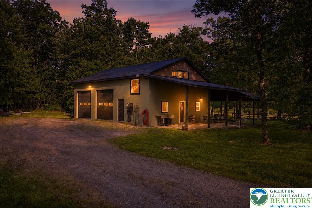 A private driveway leads to this charming garage and house nestled amongst a verdant treeline, offering serene evenings.